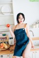 A woman sitting on a kitchen counter holding an apple.