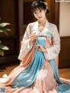 A woman in a blue and pink hanbok sitting on the floor.