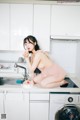 A woman sitting on top of a kitchen counter next to a washing machine.