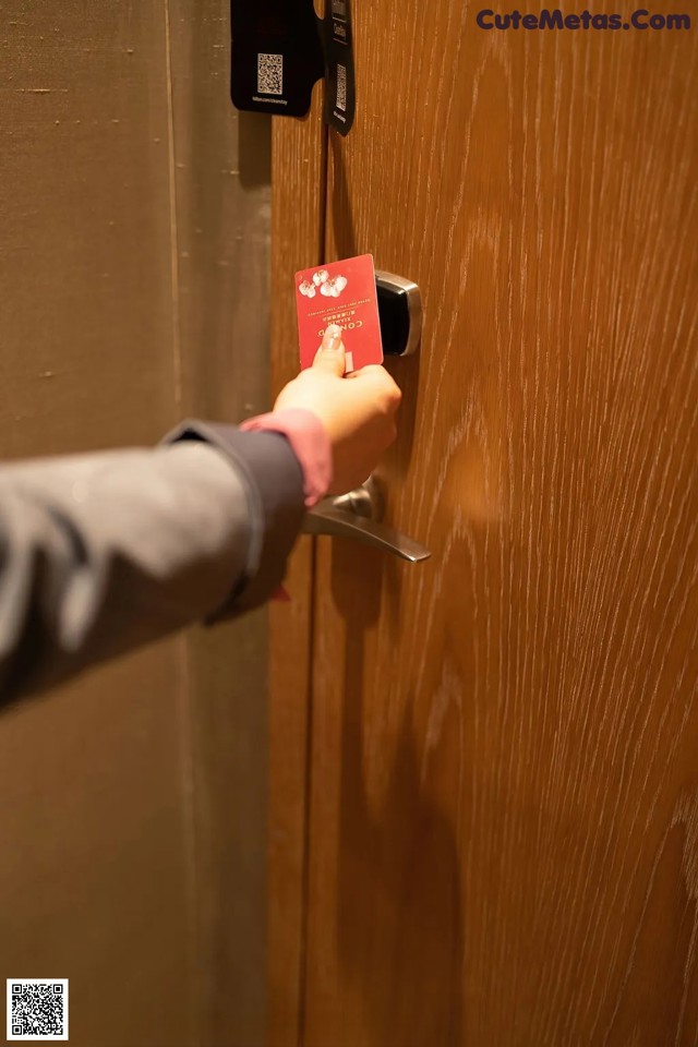 A person opening a door with a red card in their hand.