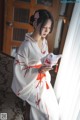 A woman in a white and red kimono holding a mask.