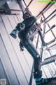 A woman in a black and blue outfit standing on a ladder.