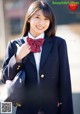 A woman in a school uniform with a red bow tie.