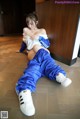 A woman in a blue and white outfit is sitting on the floor.