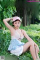 A woman in a pink hat is sitting in the grass.