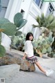 A woman sitting on a rock in front of a cactus.