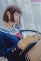 A woman in a sailor outfit reading a book.